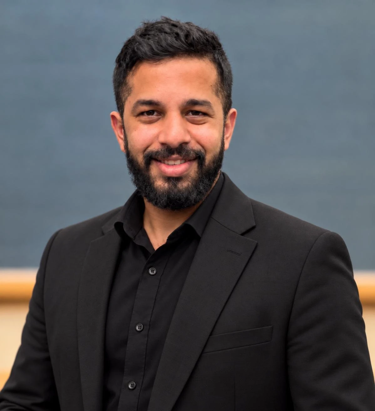 Muhammad Arslan in a black jacket against a grey background